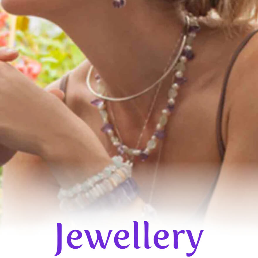 A close up of a lady wearing crystal chip bracelets, a crystal necklace and gemstone earrings