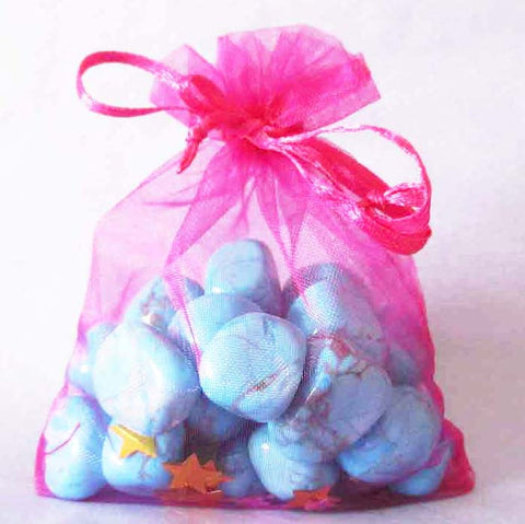 a pink organza pouch full of pale blue turquoise howlite tumble stones